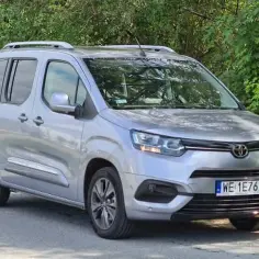 Srebrny Toyota Proace City Verso zaparkowany przy zielonym lesie. Idealny na rodzinne wycieczki.