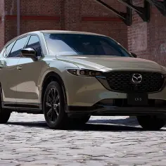 Mazda CX-5 w kolorze zielonym, zaparkowana na bruku. Niektórzy kierowcy wyrażają negatywne opinie o tym modelu, wskazując na pewne wady.