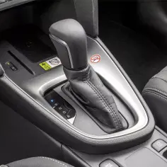 Wnętrze toyoty hev: dźwignia zmiany biegów, przycisk start/stop, gniazdo 12V i siedzenie z geometrycznym wzorem.