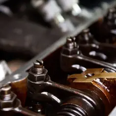 Zbliżenie na mechanizm silnika, widoczne są elementy takie jak popychacze i śruby regulacyjne, które decydują o prawidłowych luzy zaworowe.