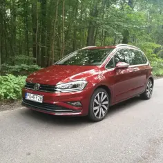 Czerwony VW Sportsvan na leśnej drodze, gotowy na przygodę.