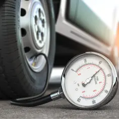 Manometr pokazuje, jak sprawdzić ciśnienie w oponach. Wąż łączący go z kołem jest widoczny.
