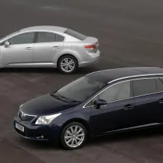 Dwa samochody: ciemnoniebieski kombi i srebrny sedan. Oba to modele Toyota Avensis T27, prezentujące różne wersje nadwozia.