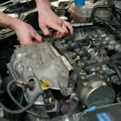 Mechanik wymienia czujnik położenia wału w silniku samochodowym.