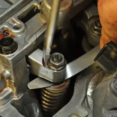 Mechanik reguluje zawory w silniku, używając śrubokręta i cienkiego metalowego listka.