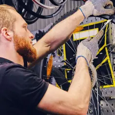 Mechanik w rękawiczkach naprawia **detkę** w rowerze.