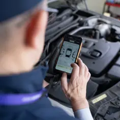 Mechanik sprawdza na telefonie raport z pomiaru lakieru i szczelin, szukając ewentualnych kody błędów.