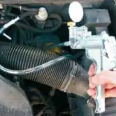 Diagnostyka Forda z kodem DTC P1335. Mechanik używa próżniomierza do sprawdzenia układu dolotowego.