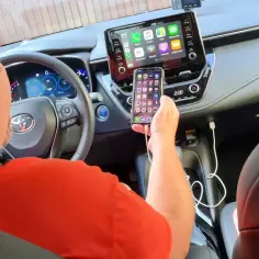Mężczyzna podłącza iPhone'a do systemu multimedialnego samochodu, pokazując, jak nowoczesne retrofity ułatwiają życie.