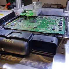 Naprawa sterownika PCR2.1 z błędem DTC P0301 Volkswagen. Na stole warsztatowym komputer silnika podłączony do testera.