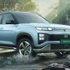 Jasnoniebieski Hyundai Creta pokonuje strumień w lesie.