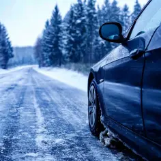 Czarne auto na śliskiej, zaśnieżonej drodze. Dobre opony Hankook opinie potwierdzają, że to pewność w zimowych warunkach.