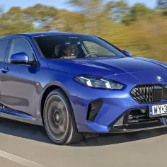 Niebieskie BMW 118i pędzi po drodze, kierowca skupiony na trasie.