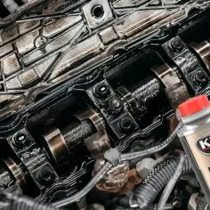 Zanieczyszczony silnik benzynowy i butelka K2 Motor Flush - najlepsza płukanka do silnika benzynowego, która przywróci mu czystość.