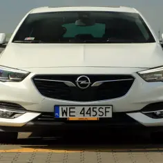 Biały Opel Insignia 2.0 Turbo z polskimi tablicami WE 445SF zaparkowany na płycie lotniska.