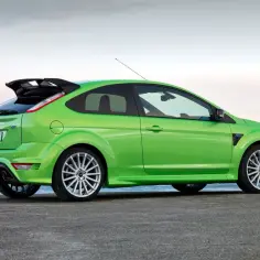 Jaskrawozielony Ford Focus RS MK2 z charakterystycznym spoilerem i dyfuzorem, zaparkowany nad morzem.
