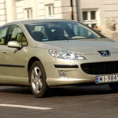 Złoty Peugeot 407 w ruchu miejskim. Wiele osób szuka peugeot 407 opinie, ten model jest dobrym wyborem.