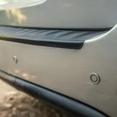 Czujniki parkowania, czyli parktronic, ułatwiają cofanie. Widoczne na zderzaku srebrnego auta.
