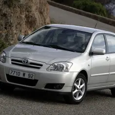 Srebrna Toyota Corolla E12 na krętej drodze, z kamienistym zboczem w tle.