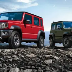 Dwa Suzuki Jimny, czerwony i zielony, na skalistym szczycie. Wyglądają jak gotowe na przygodę w stylu Suzuki Jimny 2026.