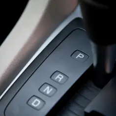Panel z przyciskami P, R, N, D. Dźwignia zmiany biegów w samochodzie z automatyczną skrzynią biegów.