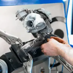 Mechanik naprawia turbosprężarkę, w tym zawór N75, używając imadła i narzędzi.
