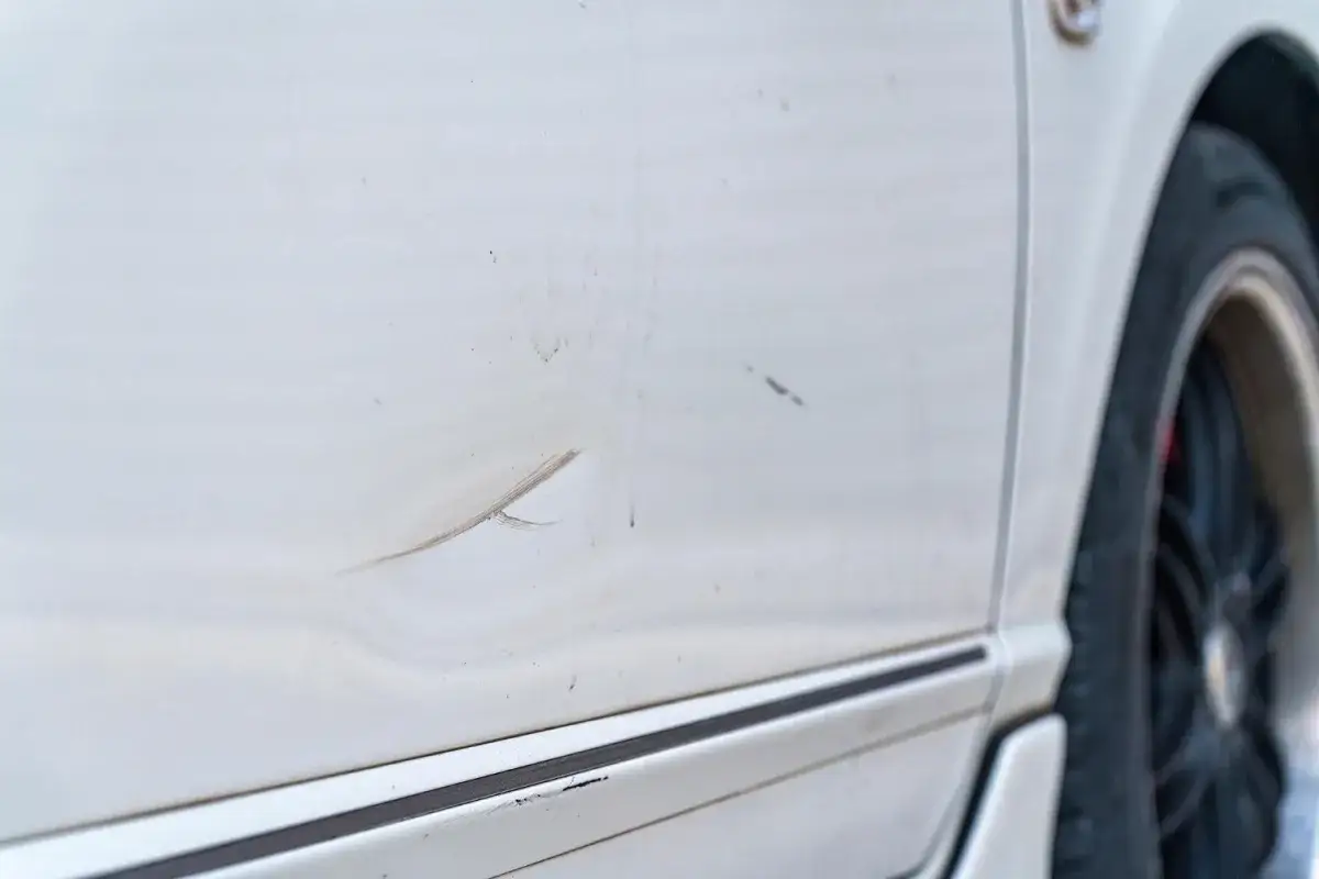 Białe auto z wgnieceniem na drzwiach. Sprawdź wyciąganie wgniotek cena i przywróć blask swojemu pojazdowi.