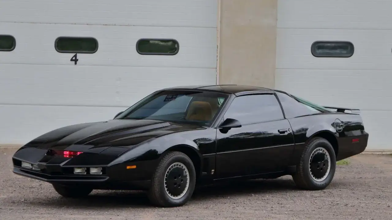 Czarny Pontiac Trans Am z czerwonymi światłami z przodu, gotowy do akcji.