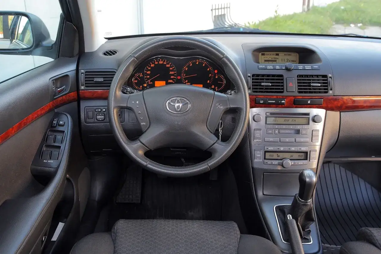 Wnętrze Toyoty Avensis T25: kierownica, deska rozdzielcza z radiem i nawigacją, dźwignia zmiany biegów.