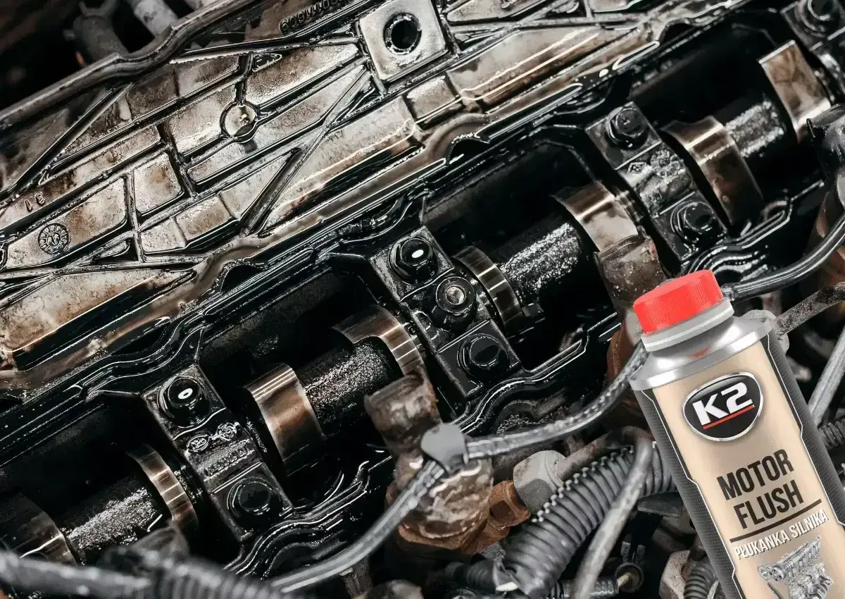 Zanieczyszczony silnik benzynowy i butelka K2 Motor Flush - najlepsza płukanka do silnika benzynowego, która przywróci mu czystość i moc.
