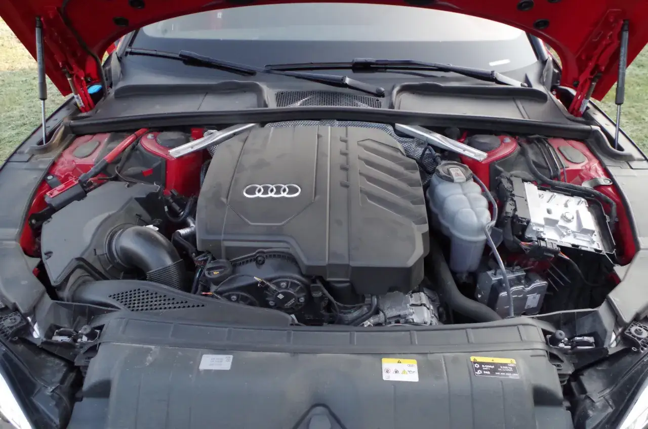 Silnik Audi A5 F5, widok z góry. Czerwona komora silnika, czarna osłona silnika z logo Audi.