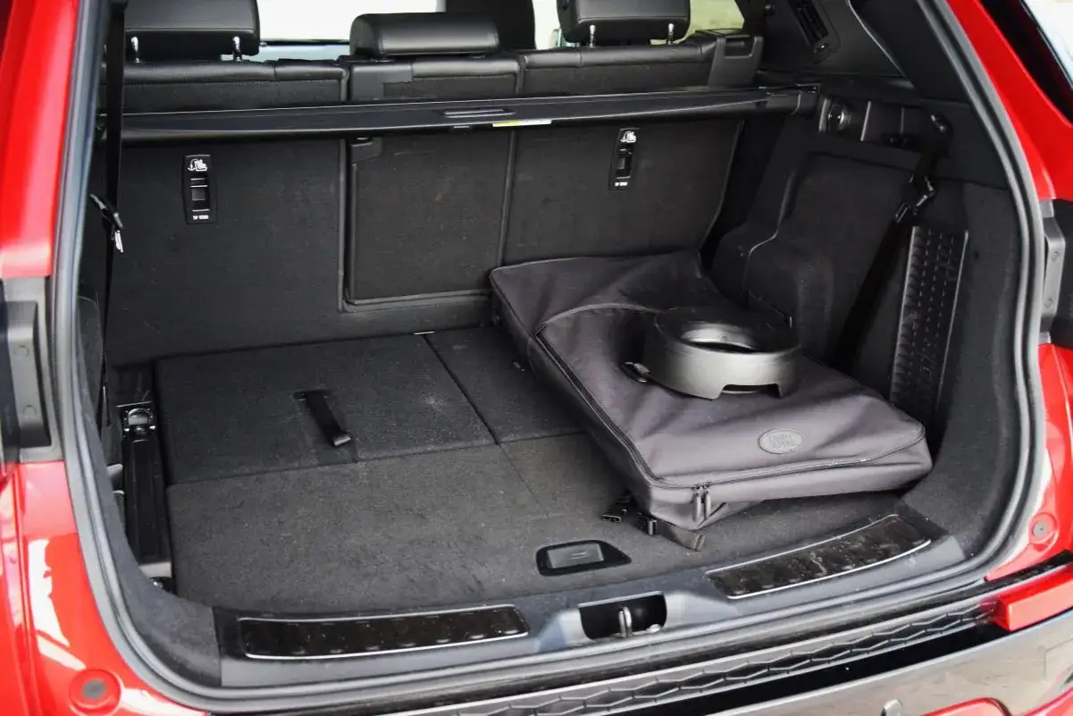 Bagażnik Land Rover Discovery Sport, z rozłożonymi siedzeniami i torbą. Wiele osób szuka land rover discovery sport opinie, by sprawdzić jego praktyczność.