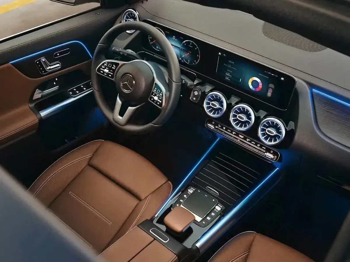 Wnętrze Mercedesa GLA z brązową tapicerką i niebieskim ambientowym oświetleniem. Czy warto kupić? Sprawdź opinie i potencjalne usterki.