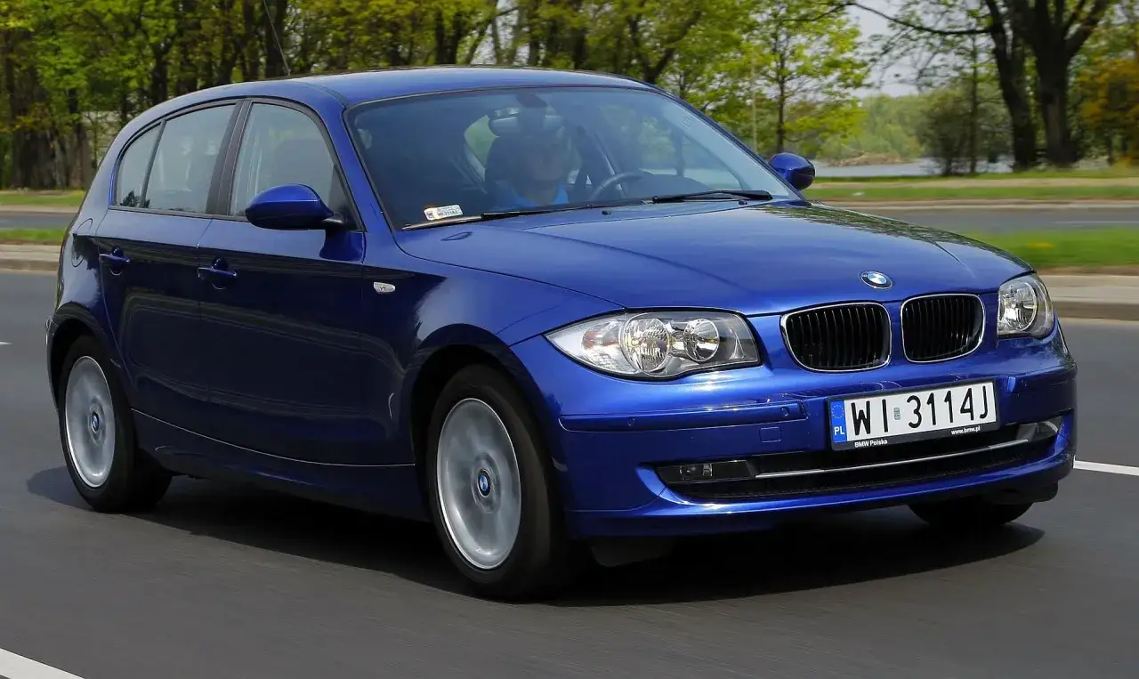 Niebieskie BMW 118d w ruchu, z widocznym kierowcą i tablicą rejestracyjną WI 3114J.