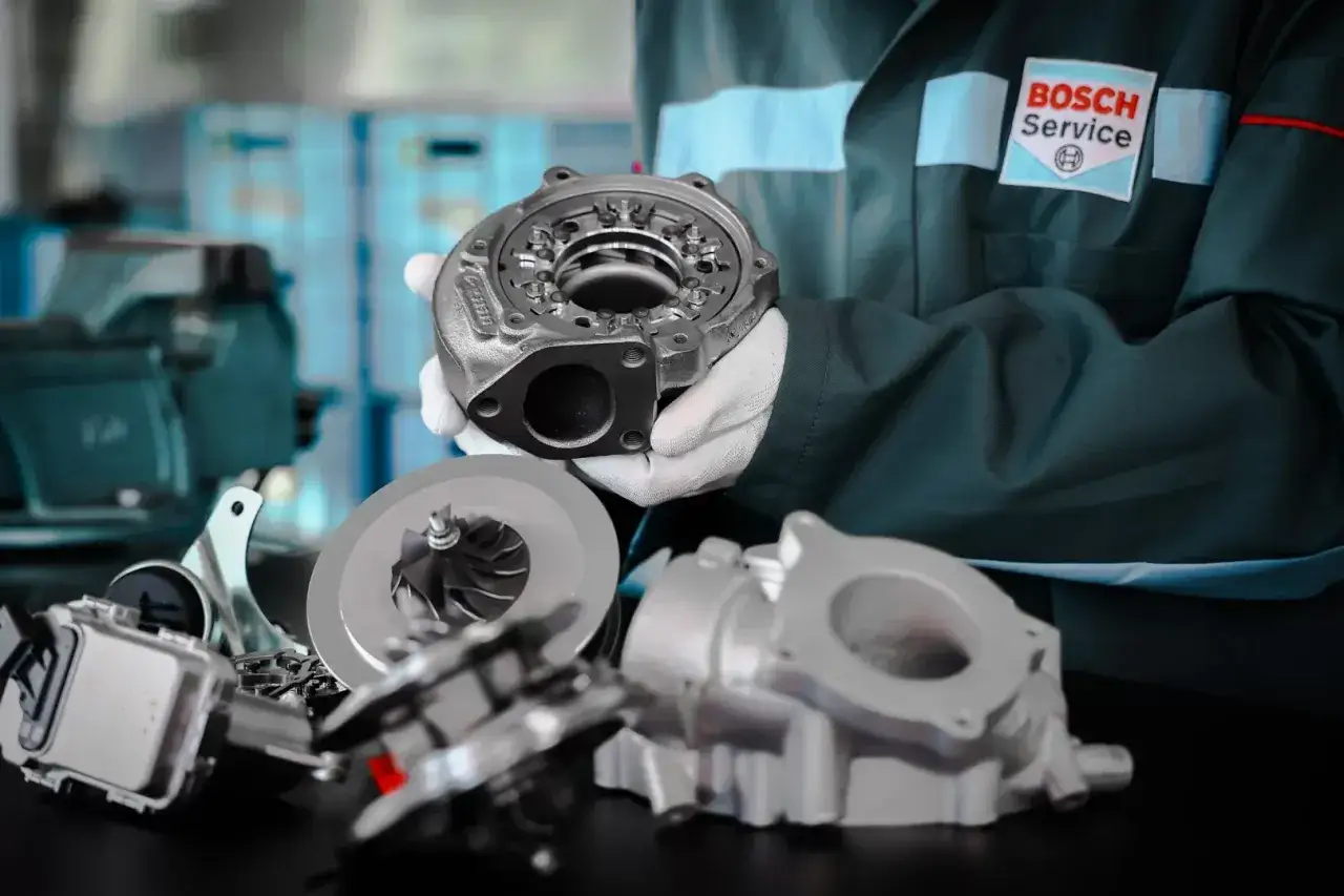 Mechanik w rękawiczkach prezentuje turbosprężarkę, kluczowy element dla sprawnego działania rozbieganego diesla.