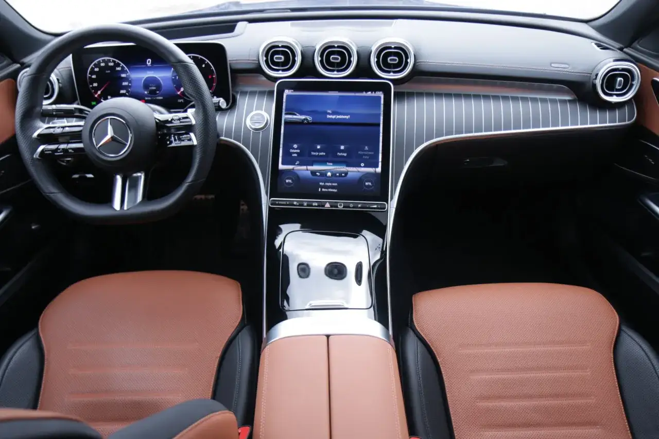 Wnętrze Mercedes C 300 z brązowo-czarną tapicerką, nowoczesnym ekranem dotykowym i cyfrowymi zegarami.