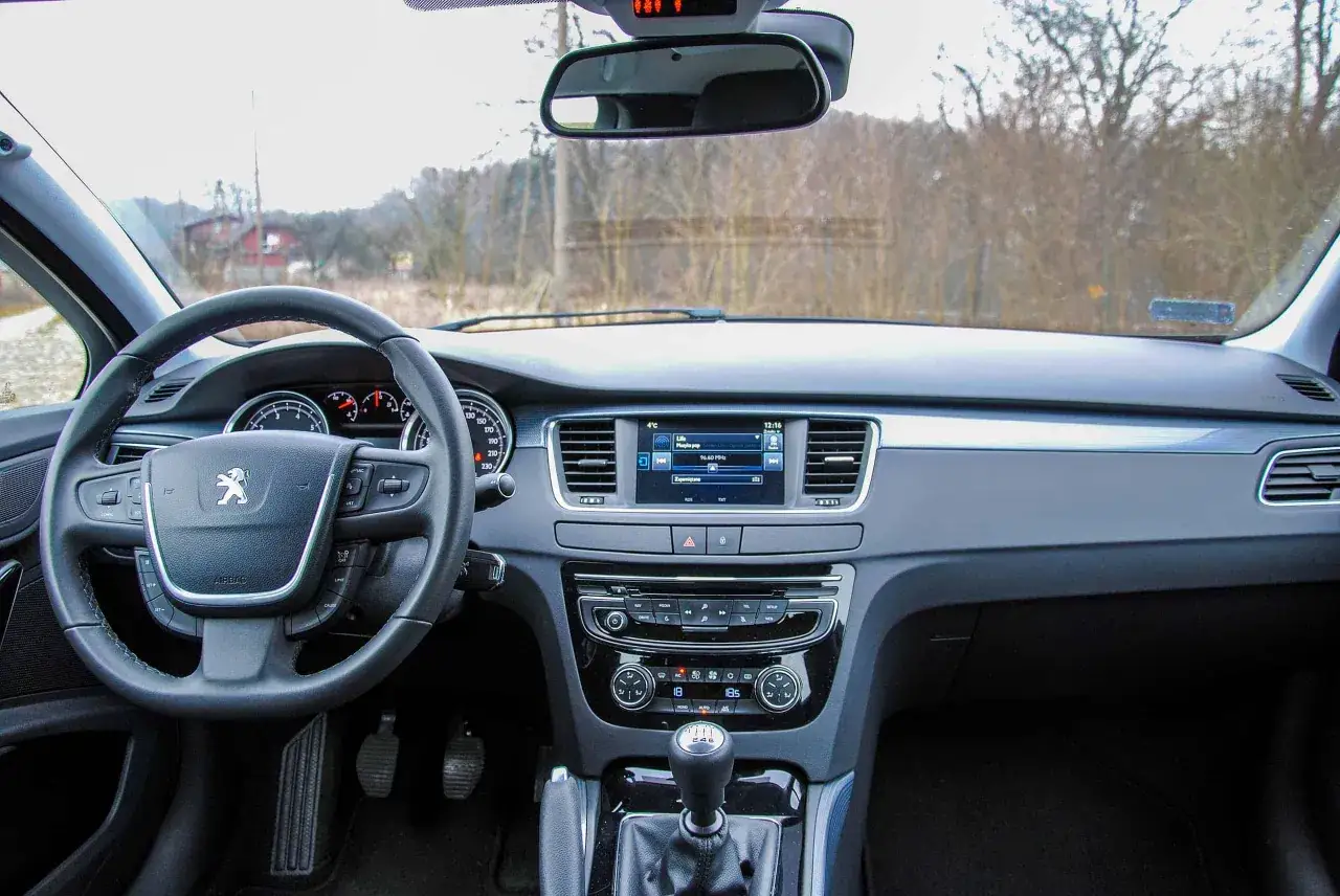 Wnętrze Peugeota 508: kierownica, deska rozdzielcza z ekranem multimediów i nawigacją. Wiele osób chwali ten model, a peugeot 508 opinie są zazwyczaj pozytywne.