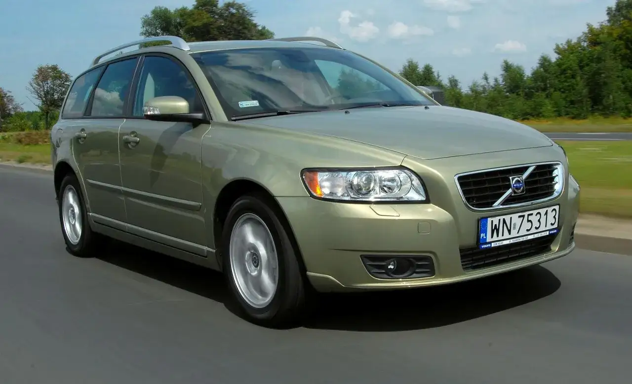 Złoty Volvo V50 w ruchu drogowym. Wiele osób chwali to auto, a jego opinie są pozytywne.
