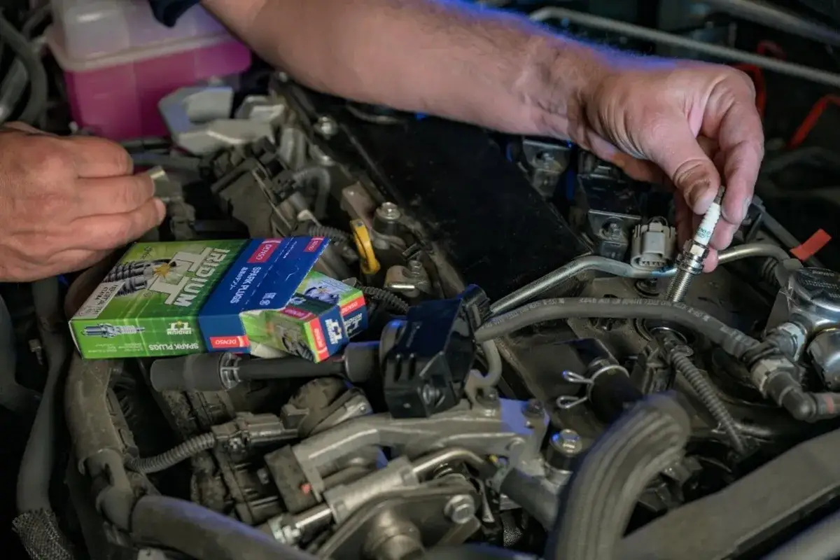 Mechanik wymienia świecę zapłonową w silniku Volkswagena, być może w celu rozwiązania problemu DTC P0301.